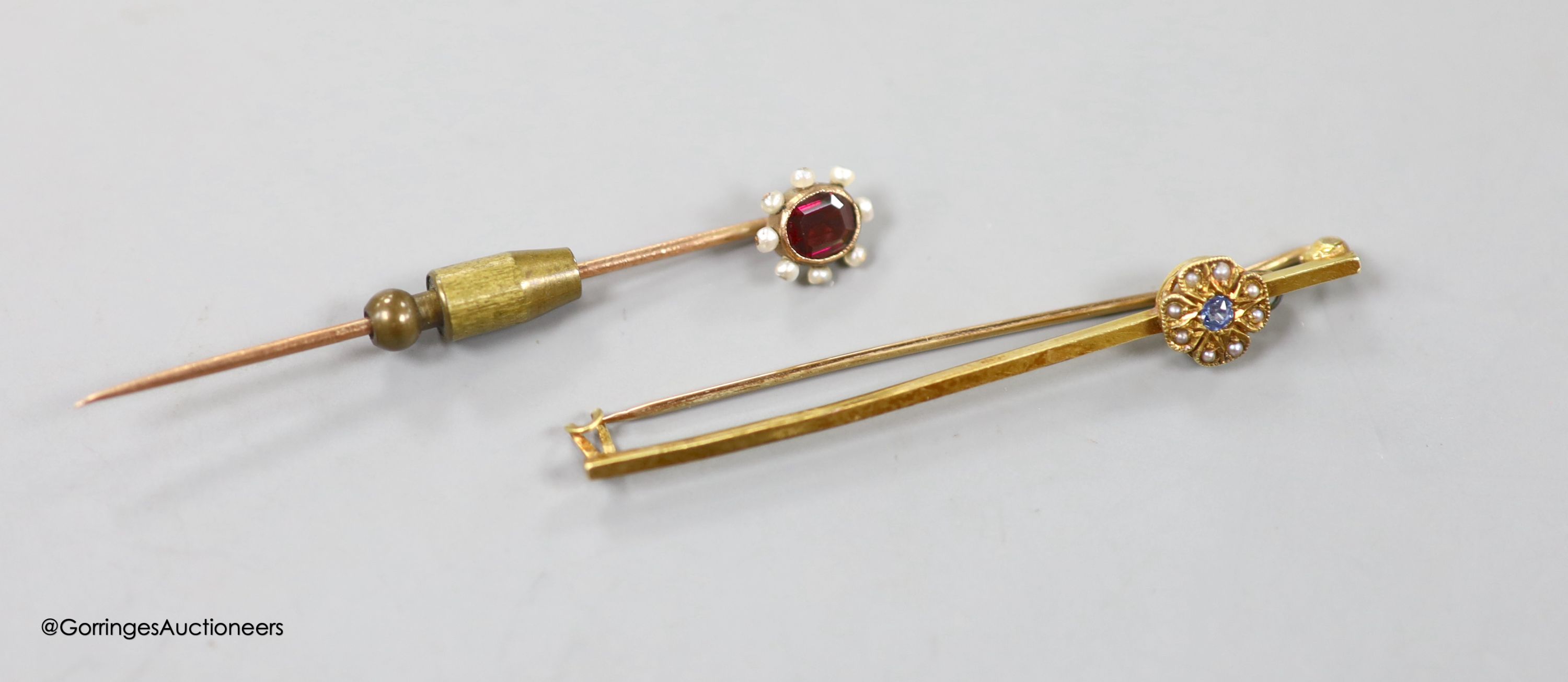 An Edwardian 15ct and gem set flower head bar brooch, 59mm, gross 3.7 grams and a yellow metal , garnet and seed pearl set stick pin, 61mm, gross weight 2.8 grams.